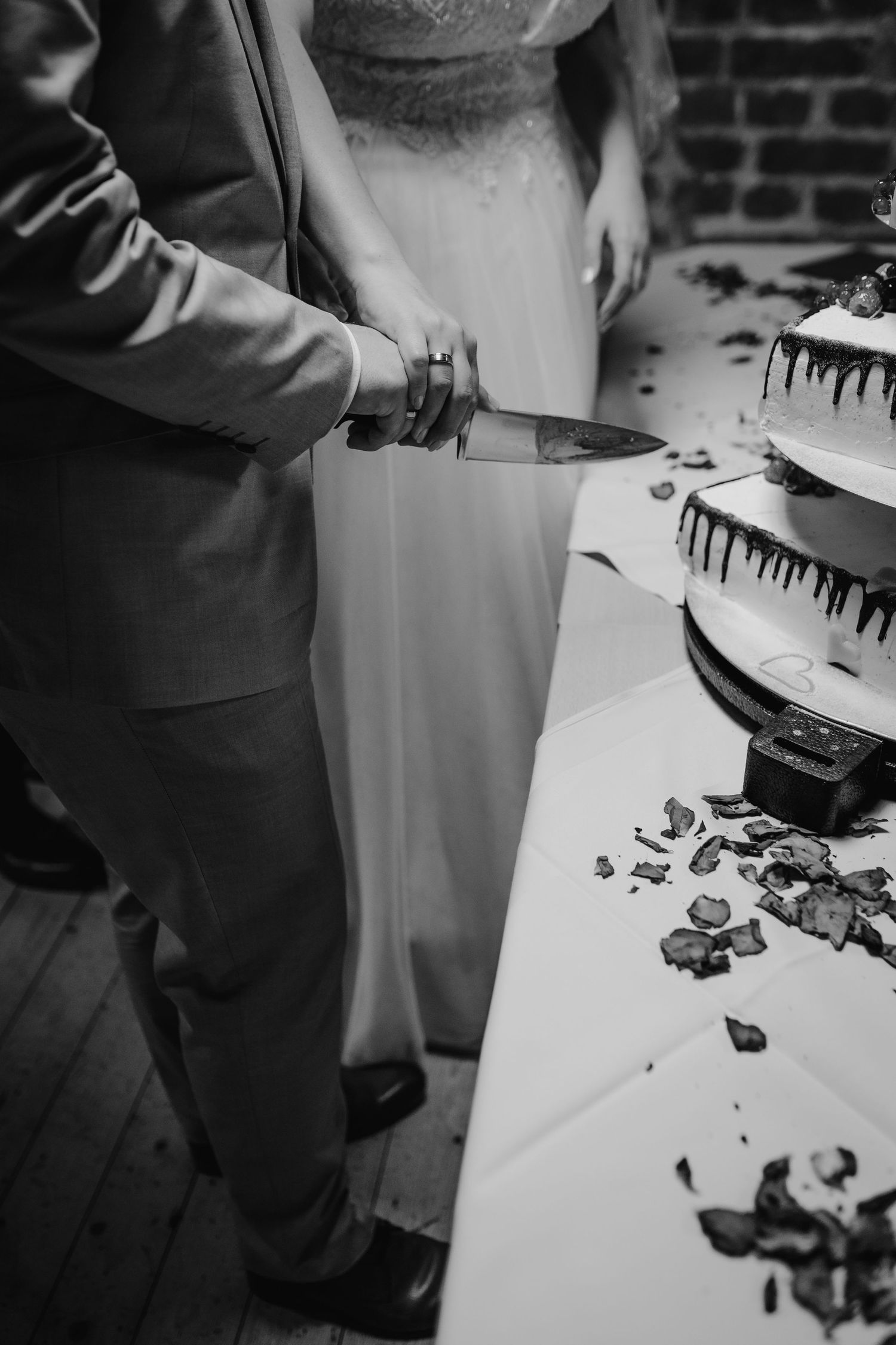 Black and white photo of wedding cake being cut at reception.