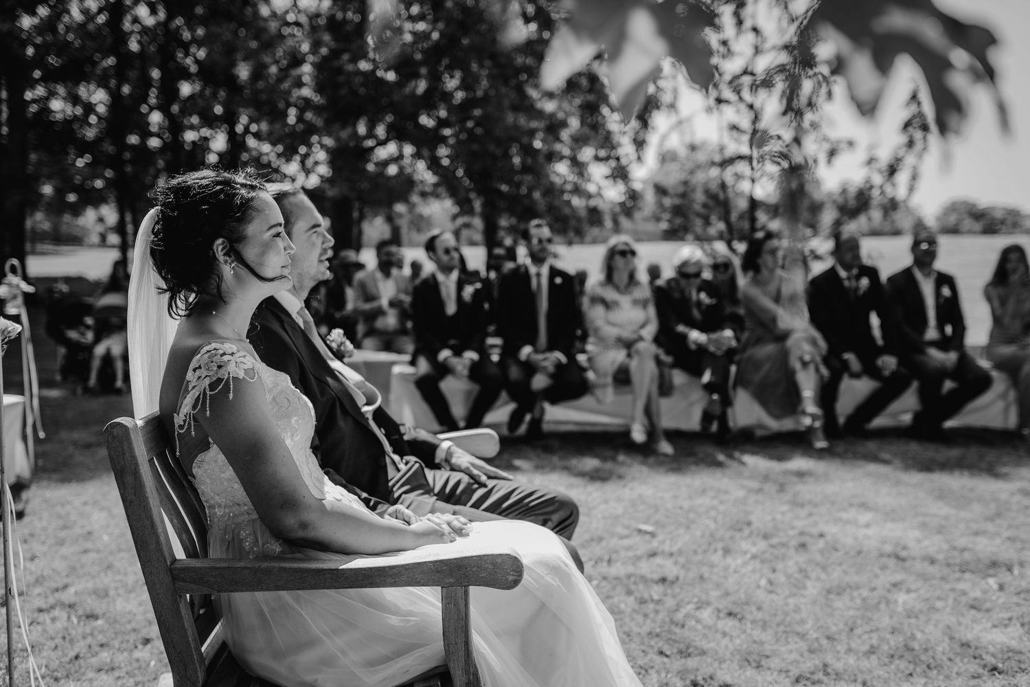 Outdoor wedding ceremony seating arrangement with guests in background.