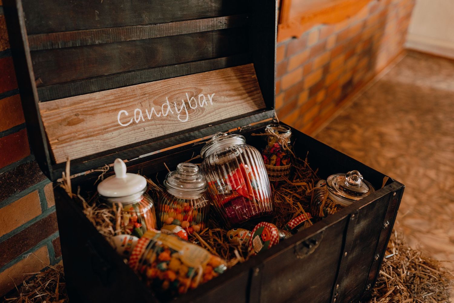 A rustic treasure chest filled with candy and treats serves as a wedding dessert table display.