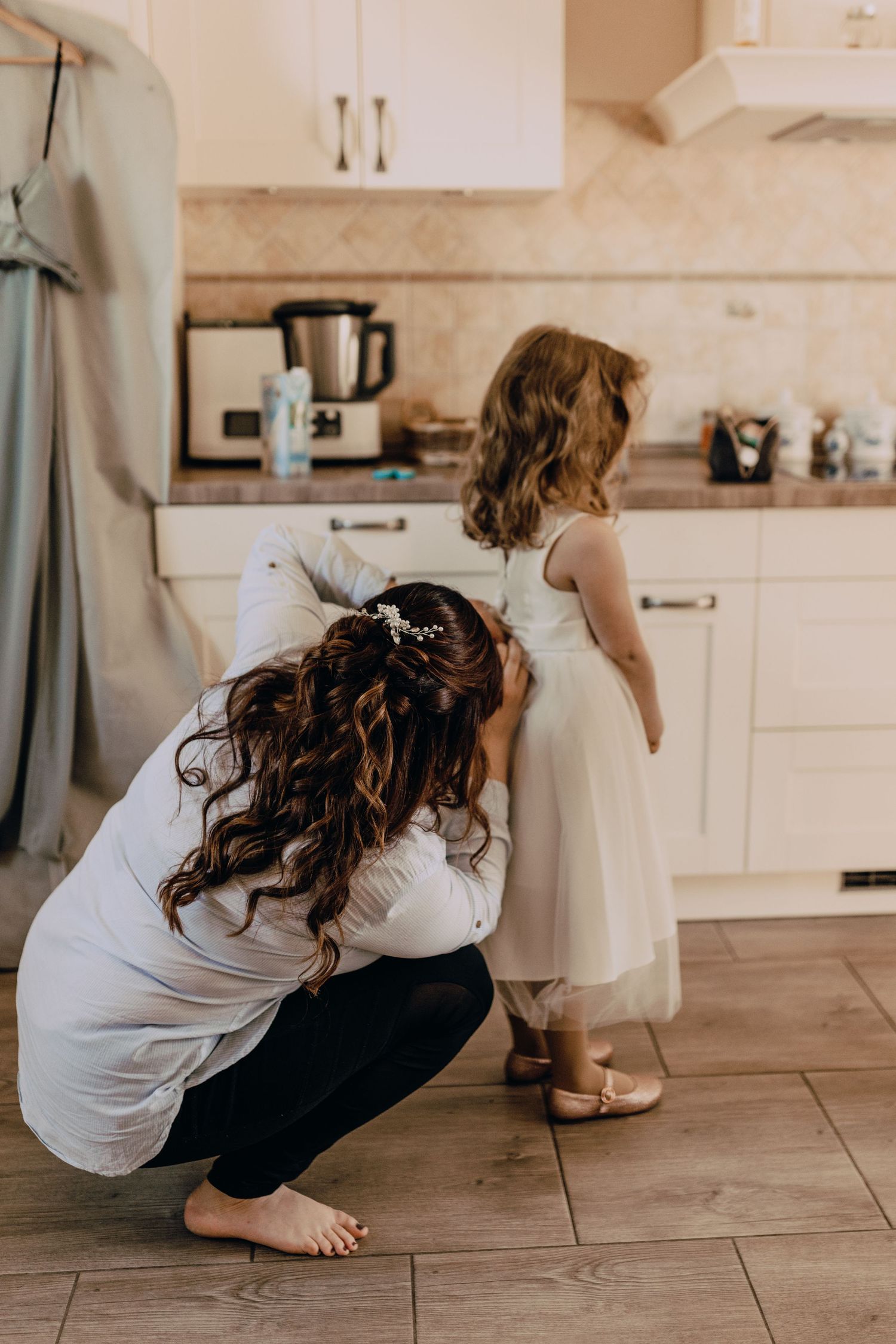 Getting ready in a kitchen before a special event with flowing dresses and natural light.