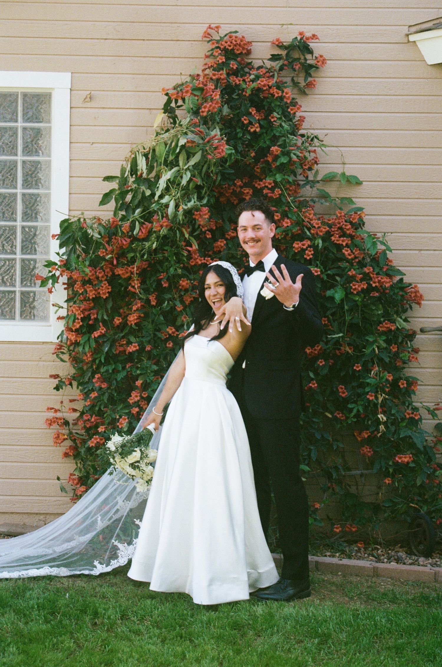film photo of bride and groom holding up rings