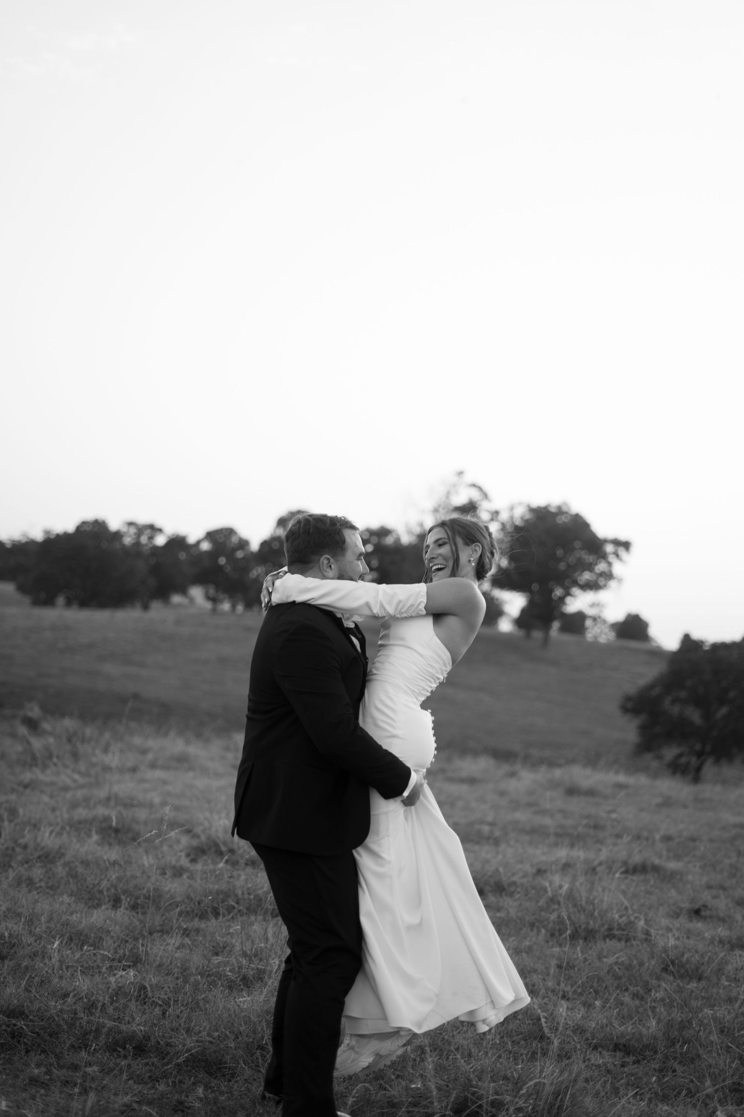 groom spinning bride around in a field