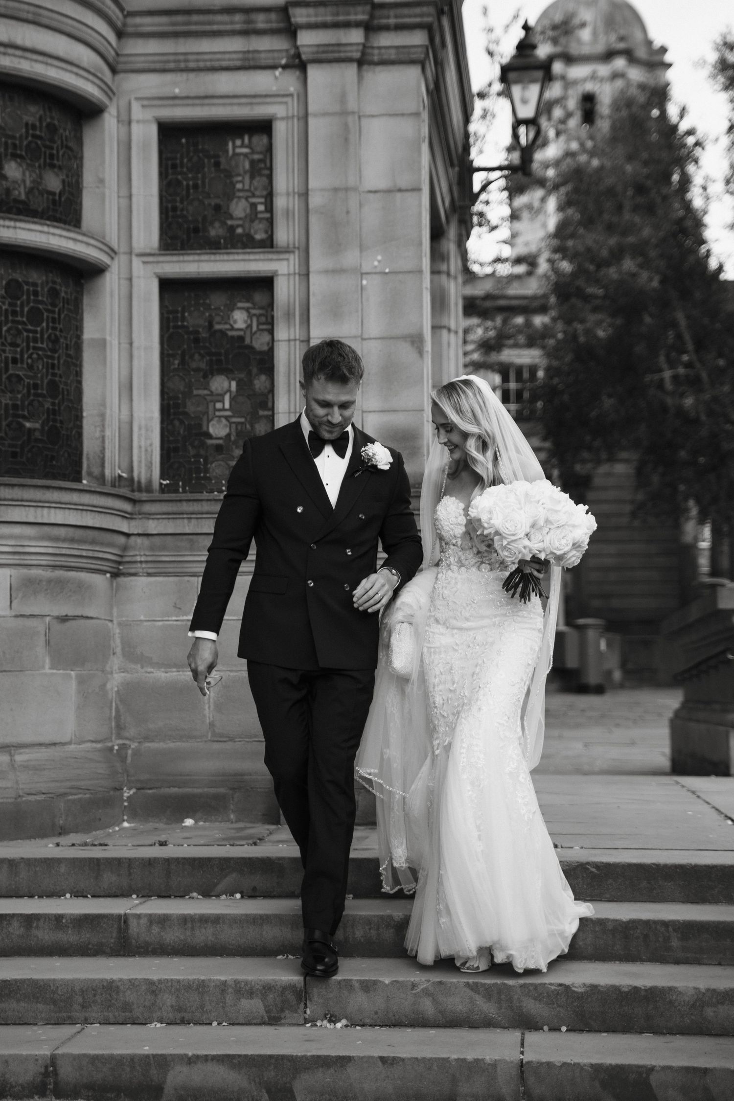 Classic black and white wedding portraits showing the couple walking along stone architecture.
