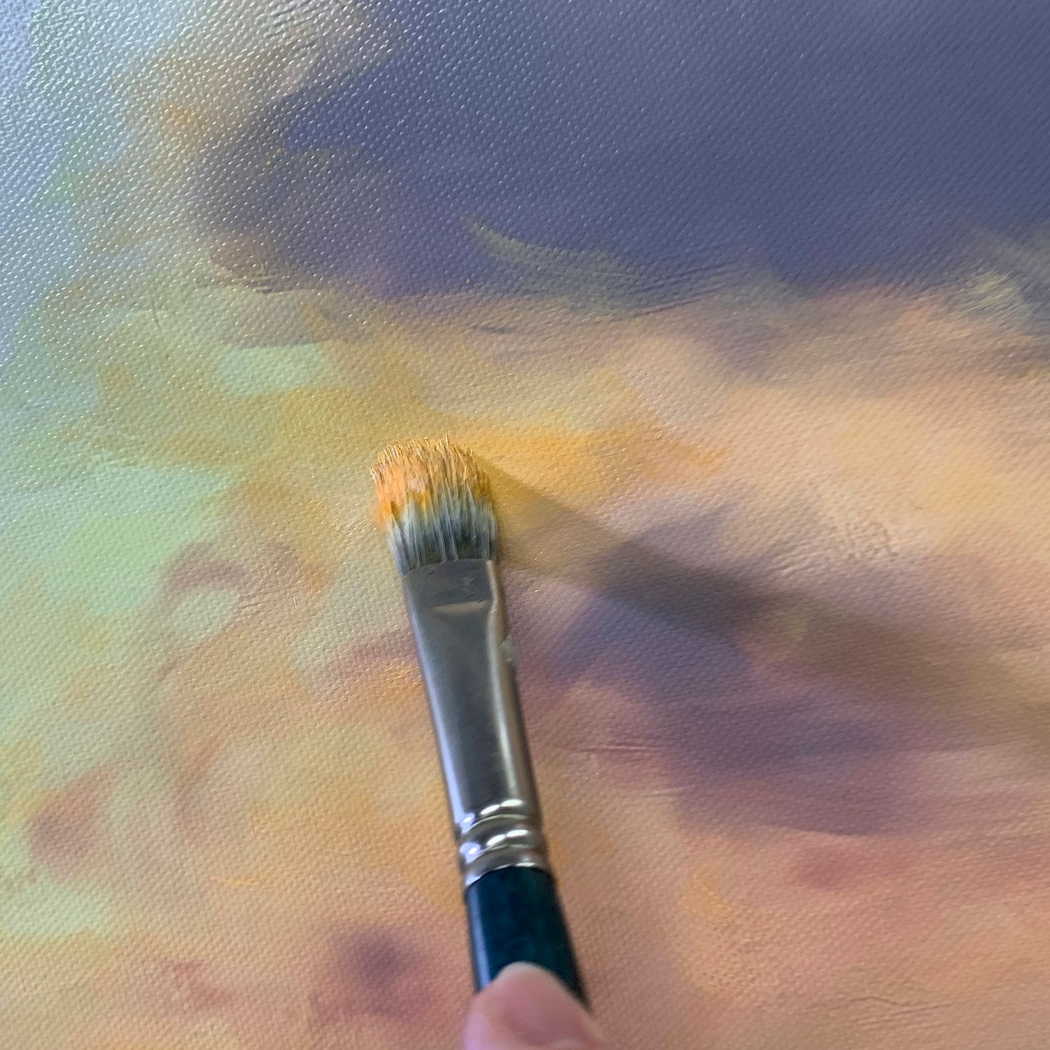 Paint brush against blended background of purple and yellow tones in artistic composition.