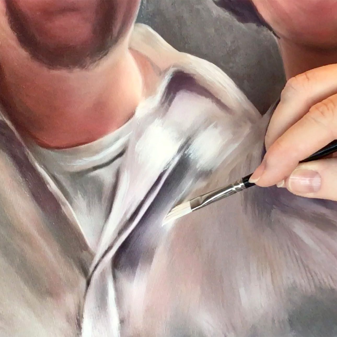 Close-up detail of an artist painting clothing texture in an oil portrait.