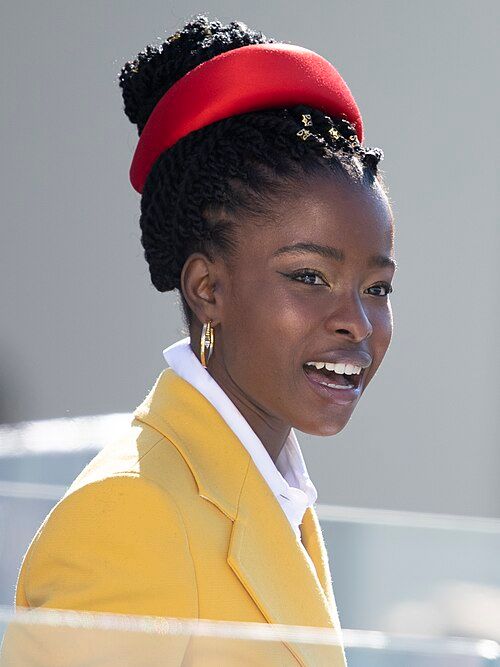 Amanda Gorman wearing her iconic yellow jacket and red headband.