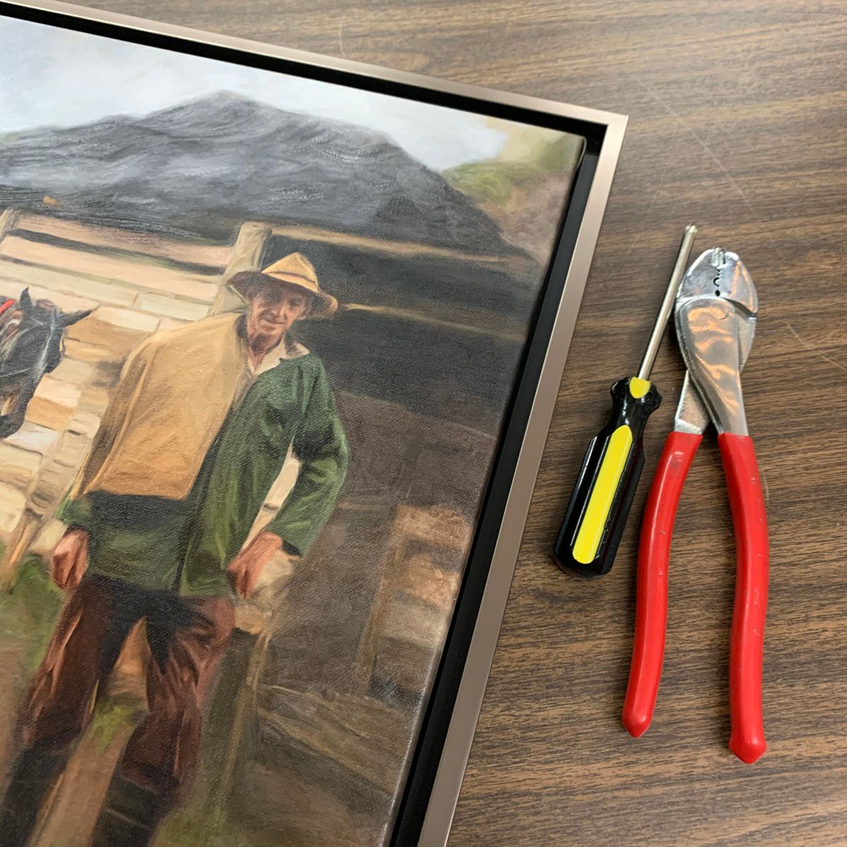 Piece of artwork being framed, with tools on a table.