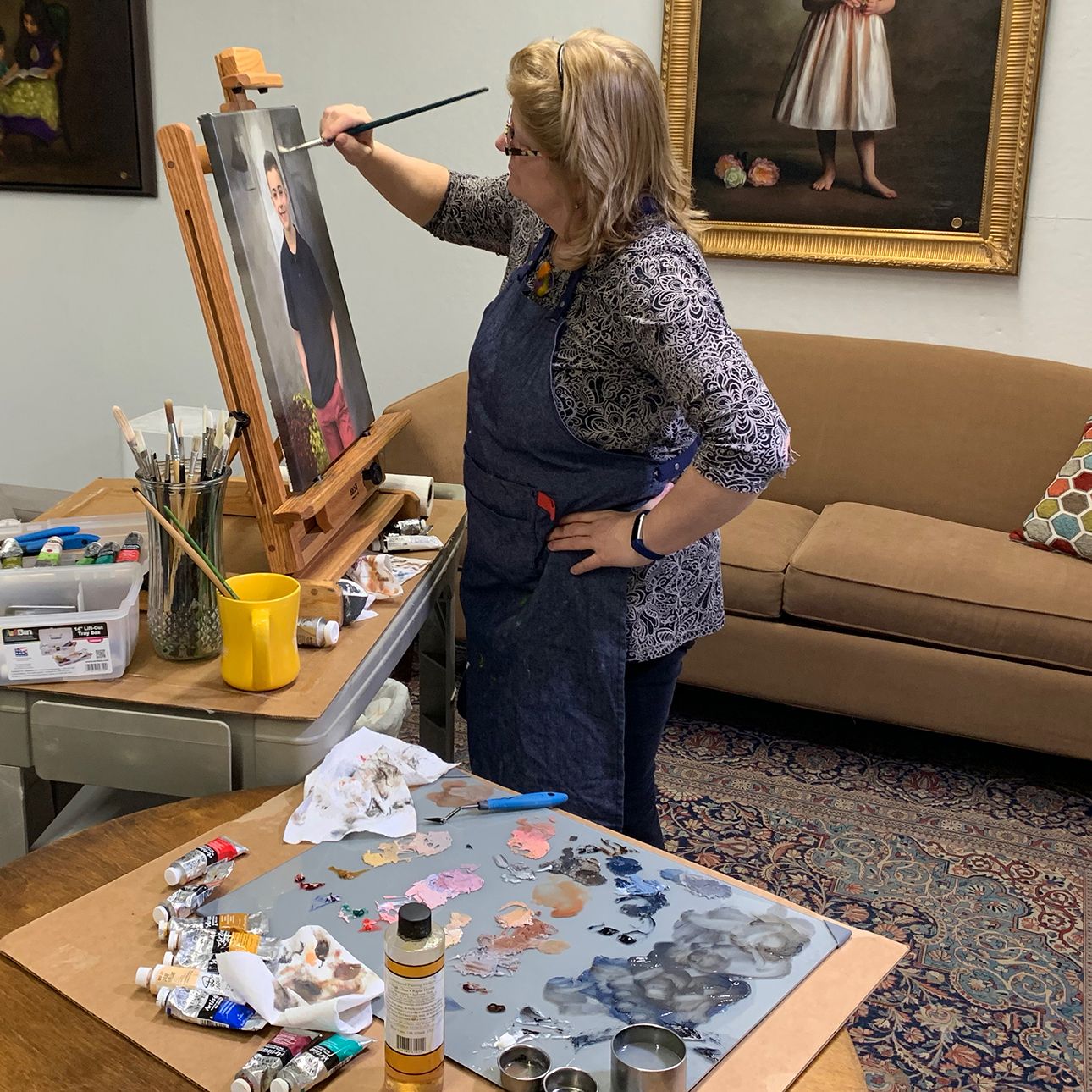 Artist Bobbie Bush painting at an easel in her studio.