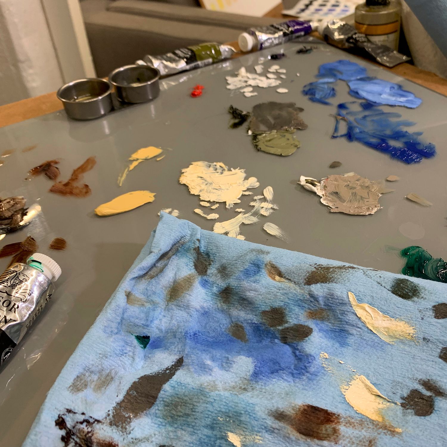 Artist's palette with various paint colors and brushmarks on a gray surface.