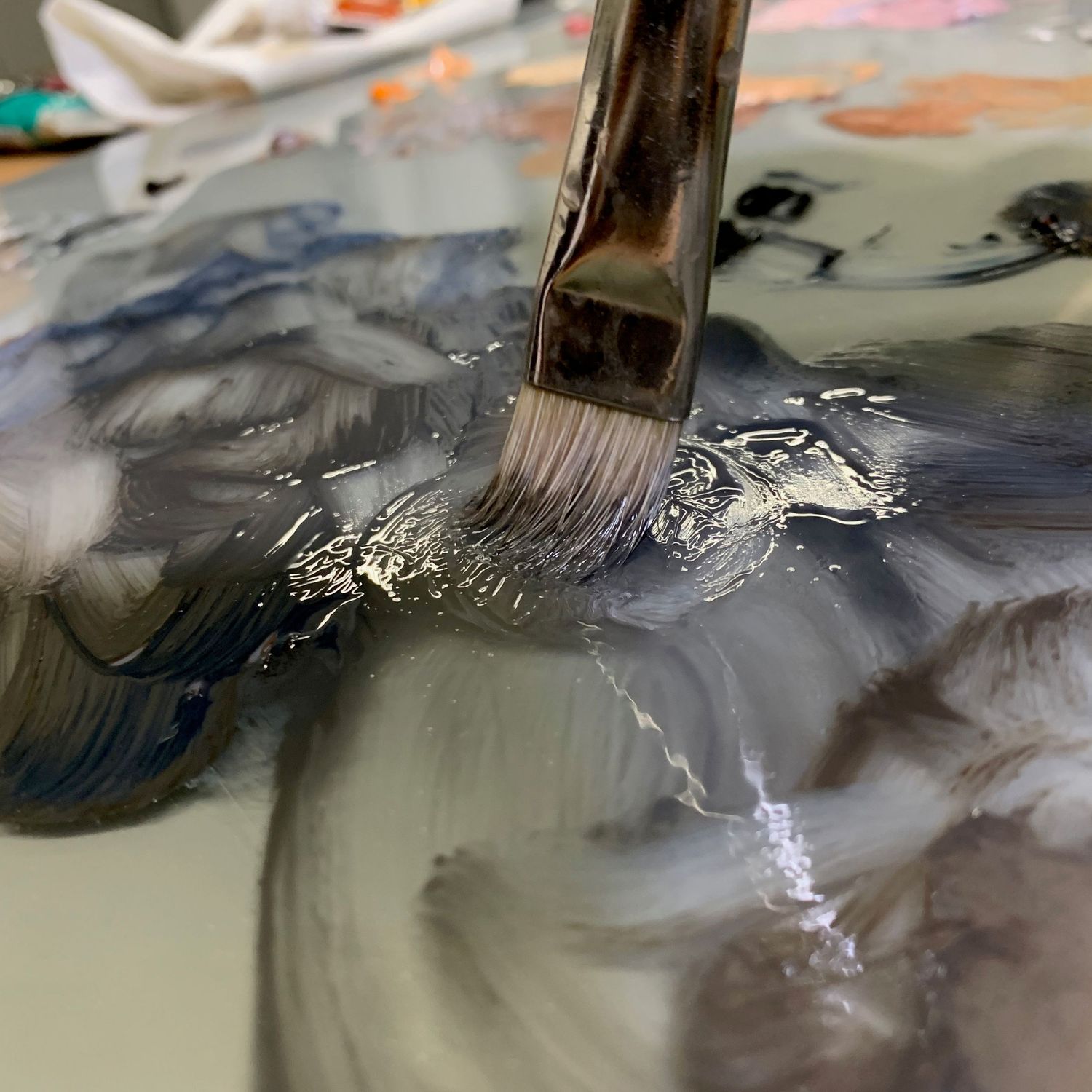 Close-up of a paintbrush blending paint colors on a painter's palette.