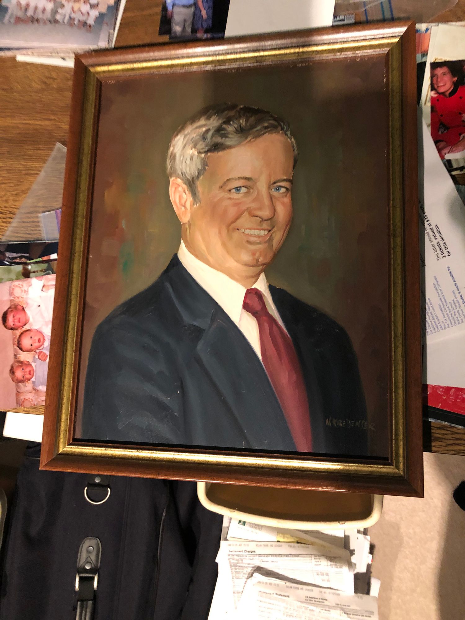 A framed formal portrait of a father wearing in dark suit and red tie.