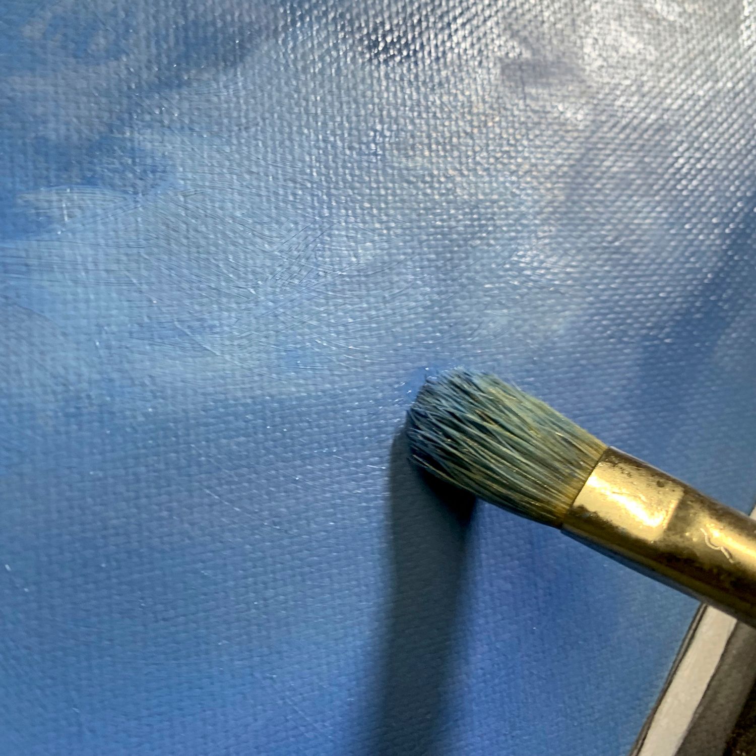 Work in progress. Paint brush against applying blue paint to the canvas.