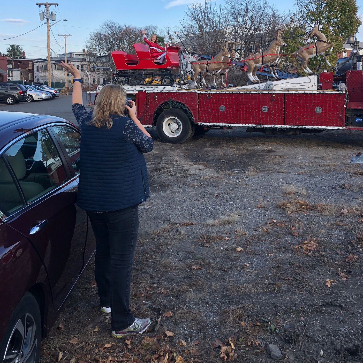 Capturing photos of a holiday scene featuring a red firetruck with a santa sleigh.