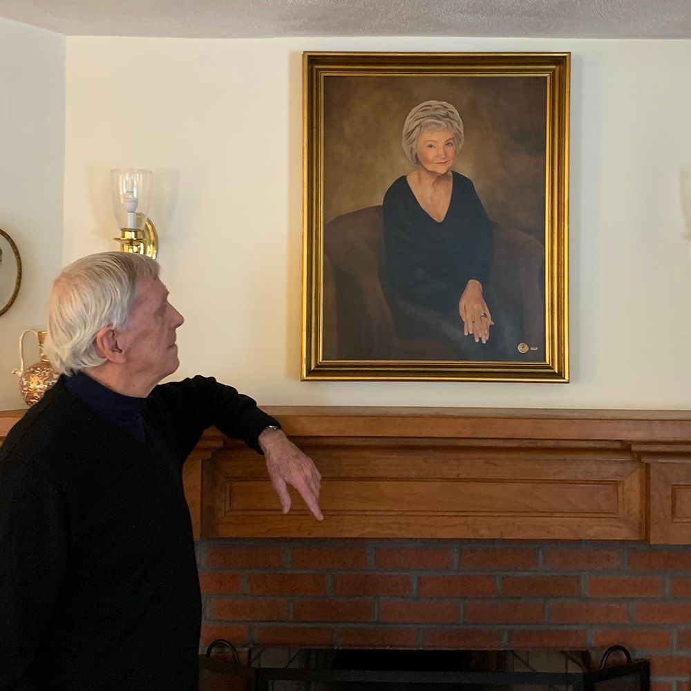 A husband admiring the painted portrait of his late wife, now displayed over his mantle.