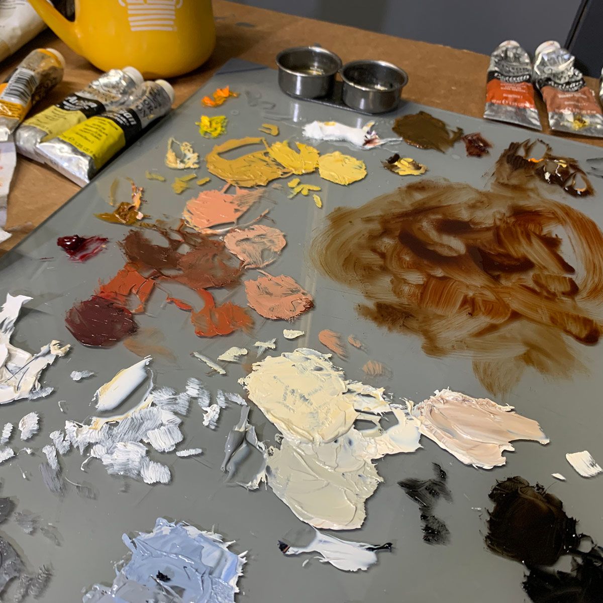 Artist's palette with various mixed skin tone paint colors and supplies.