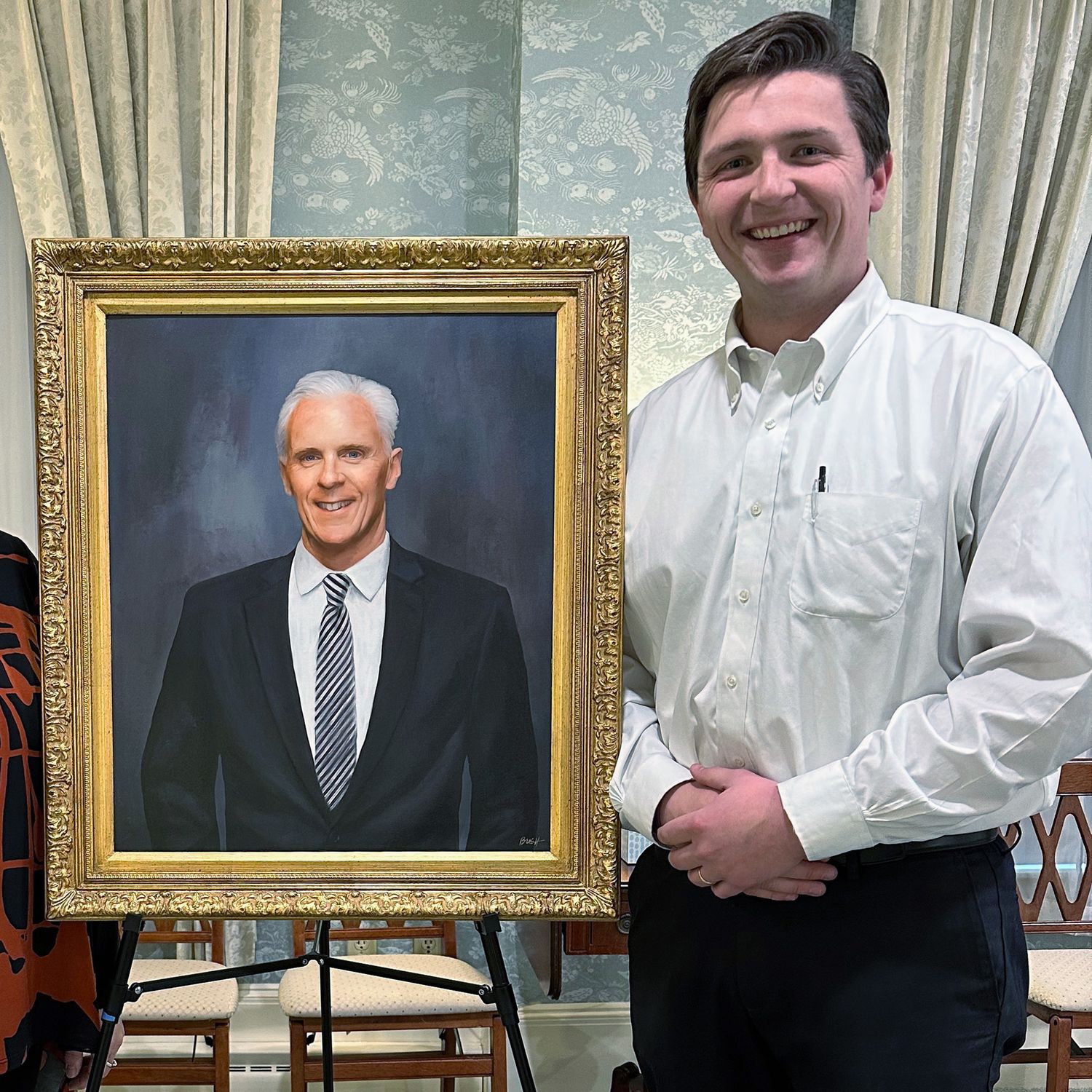 A client proudly standing next to his father's memorial portrait painting at the unveiling.