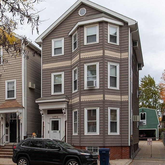 Source photo for a house portrait. Three-story house with distinctive bay windows and white trim on a residential street.