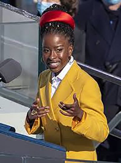 Amanda Gorman at President Biden's inauguration, wearing her iconic yellow jacket and red headband.