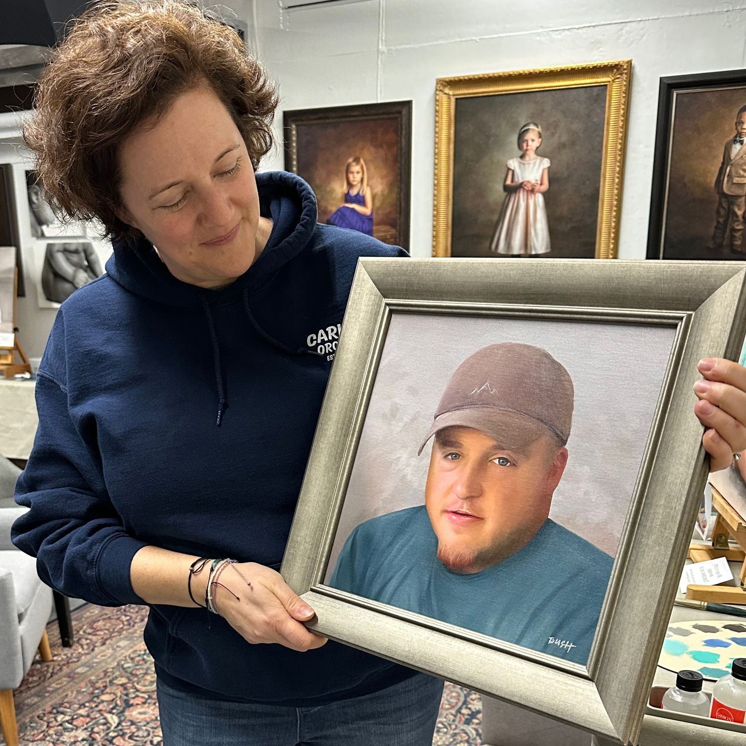 Client proudly holding a memorial portrait of her brother, commissioned as a way to honor him.