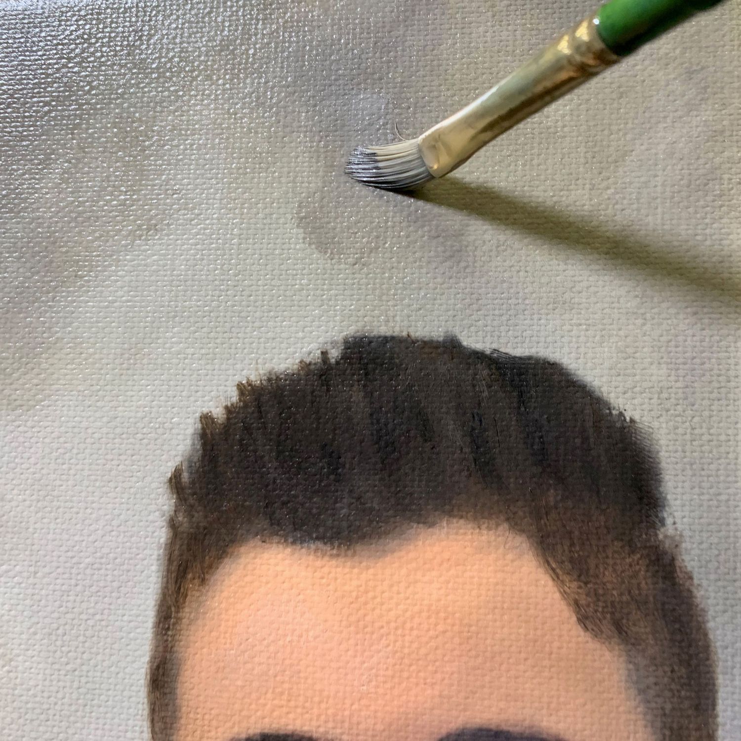 A paintbrush applying paint details to a portrait canvas.
