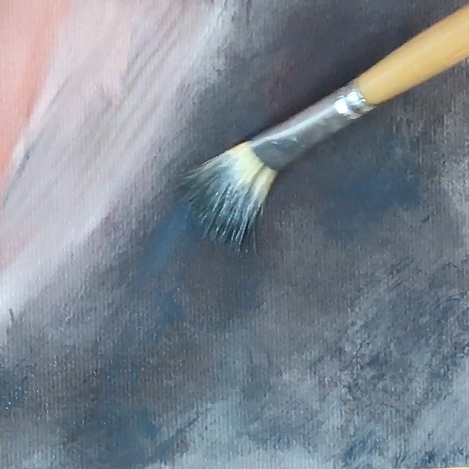 Paint brush with splayed bristles against a gray and pink painted background.