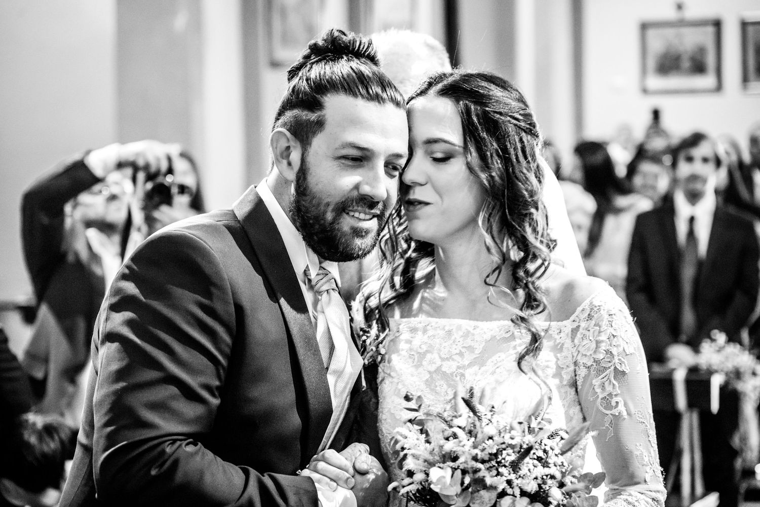 Ritratto in bianco e nero di un tenero momento in chiesa di matrimonio con bouquet.