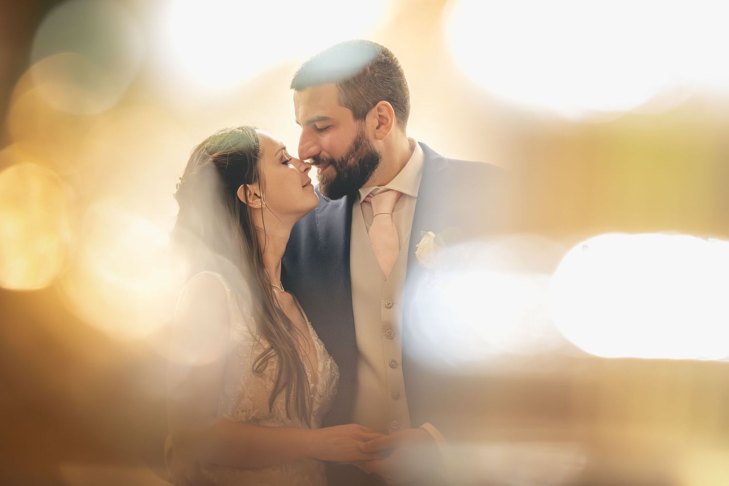 Ritratto di matrimonio romantico di una coppia che condivide un momento di tenerezza con una morbida illuminazione dorata sullo sfondo.