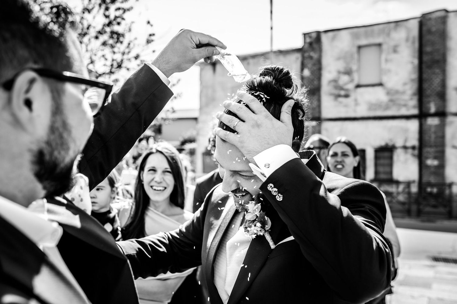 Foto in bianco e nero di un matrimonio con ospiti all'aperto durante il lancio del riso.