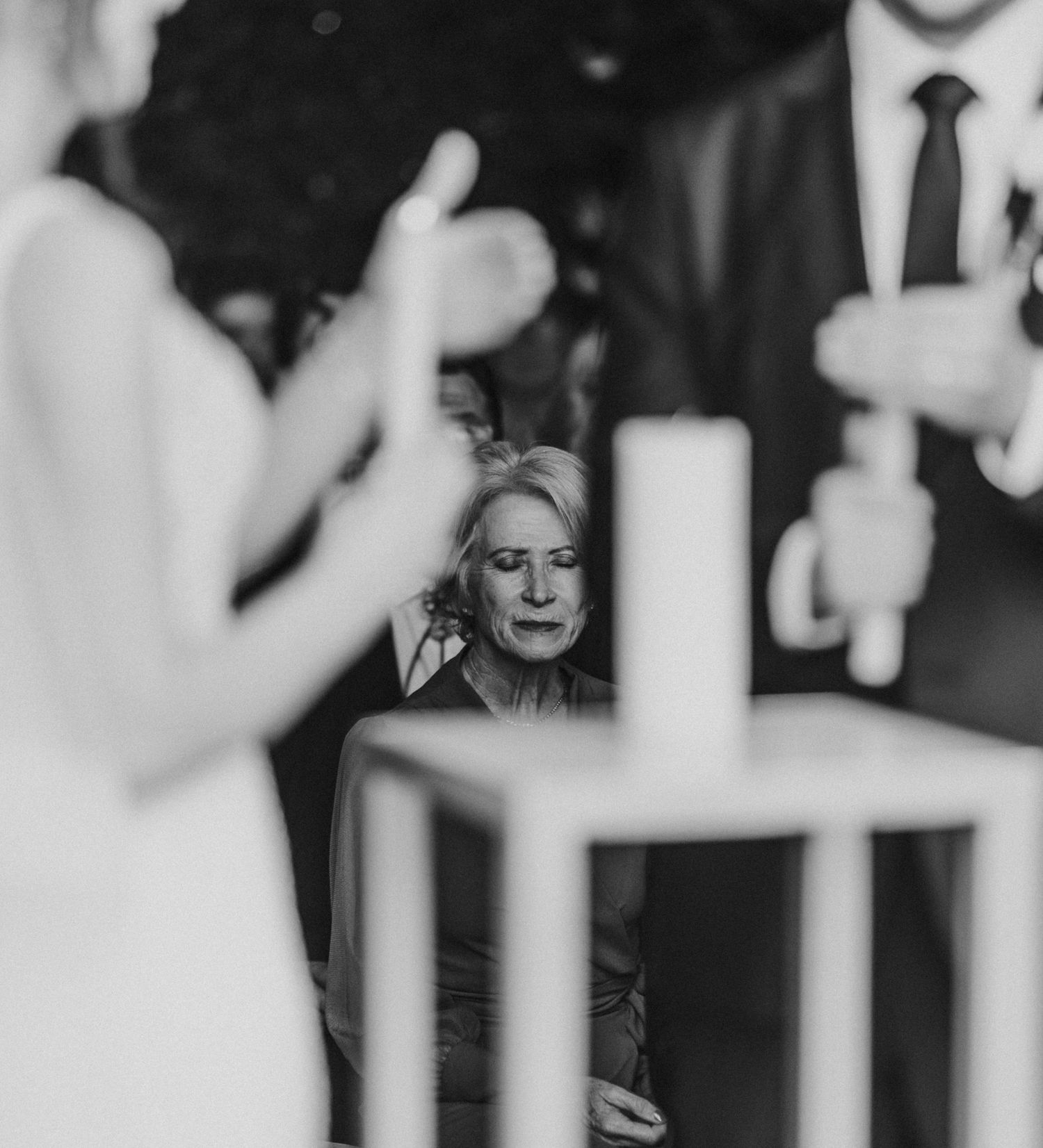 Emotional wedding guest watching couple perform unity candle ceremony in black and white.