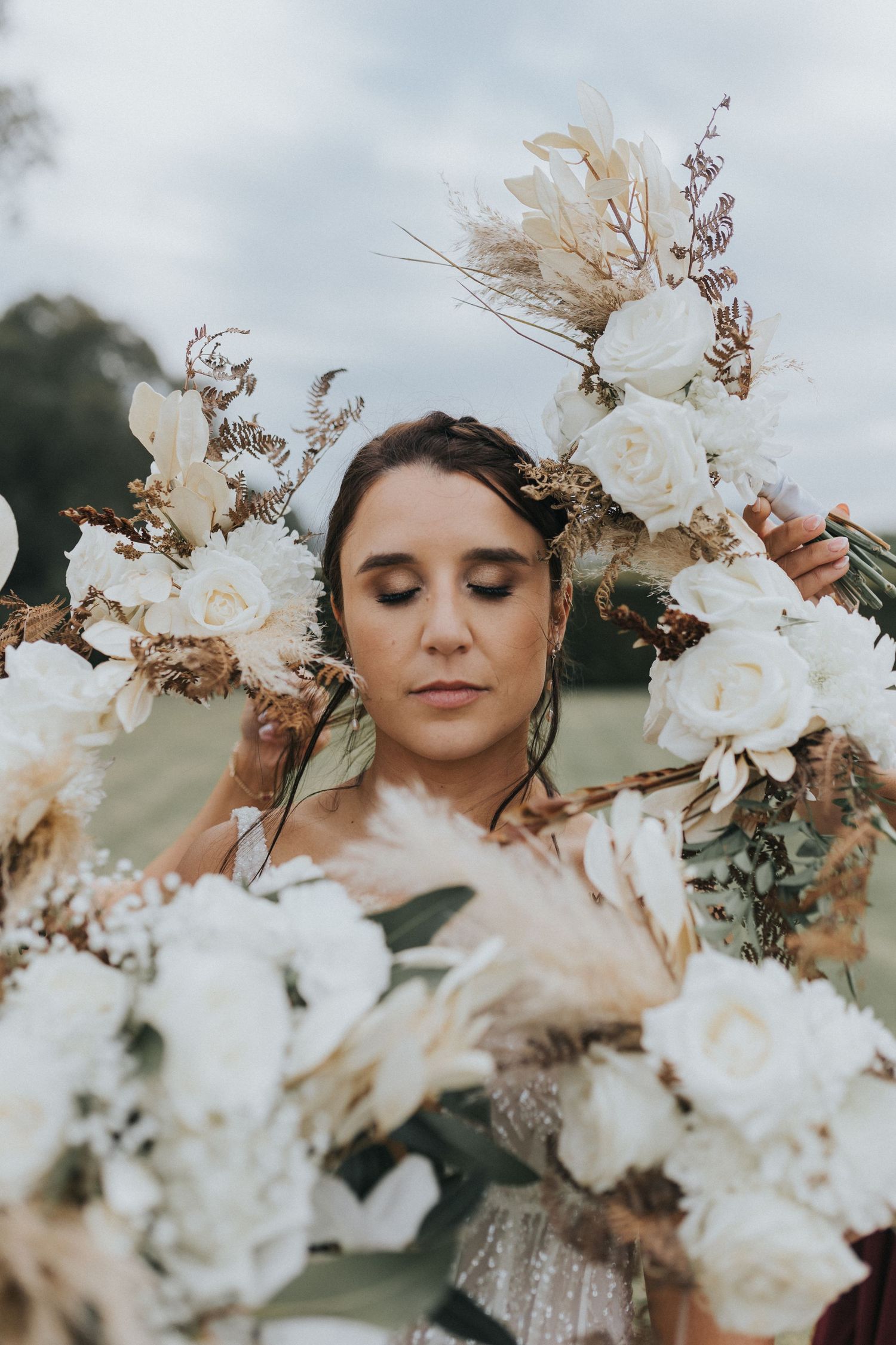 Bride surrounded by stunning boho white and gold floral bouquets with dried pampas grass.