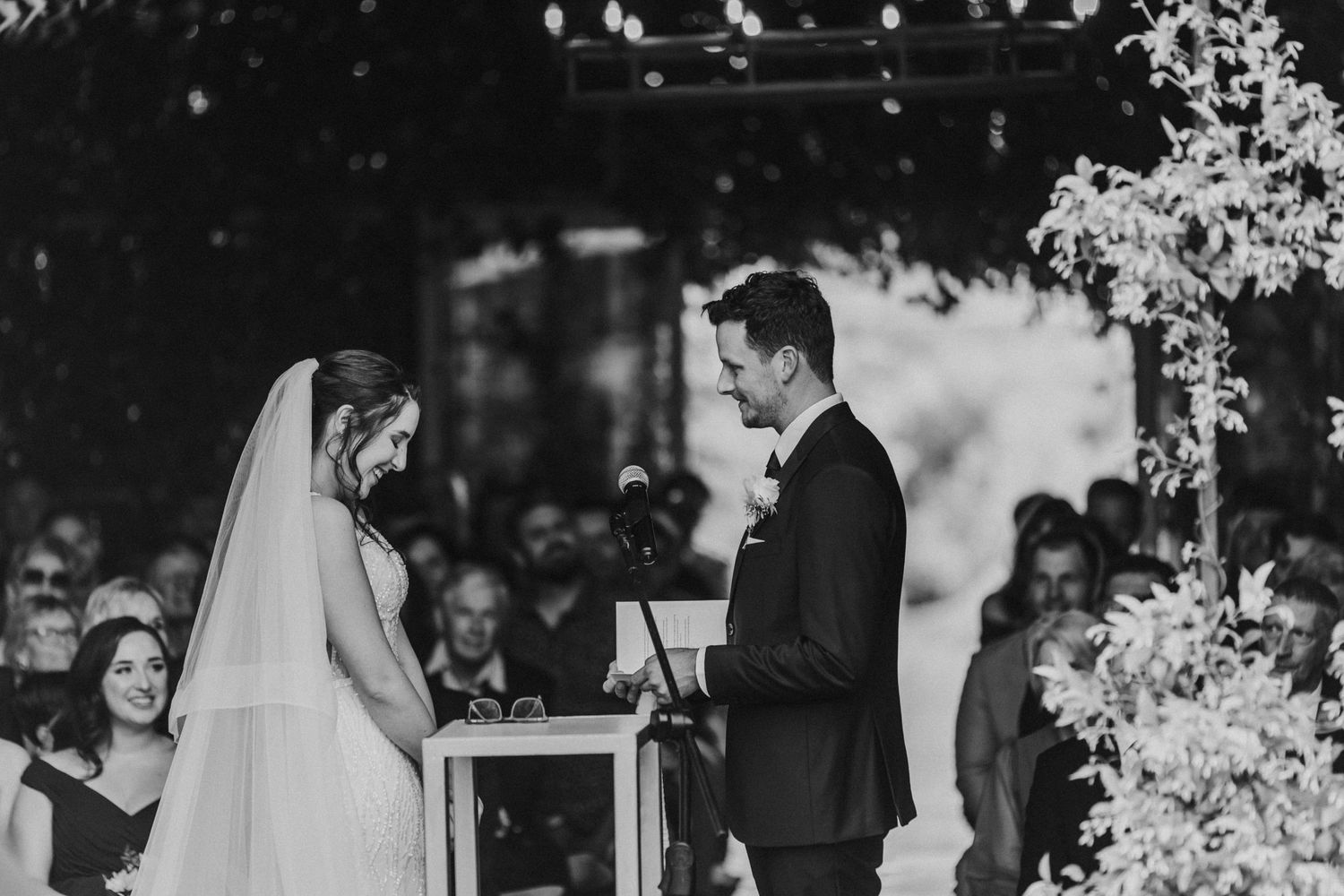 Bride and groom exchange vows at outdoor wedding ceremony altar decorated with white florals.