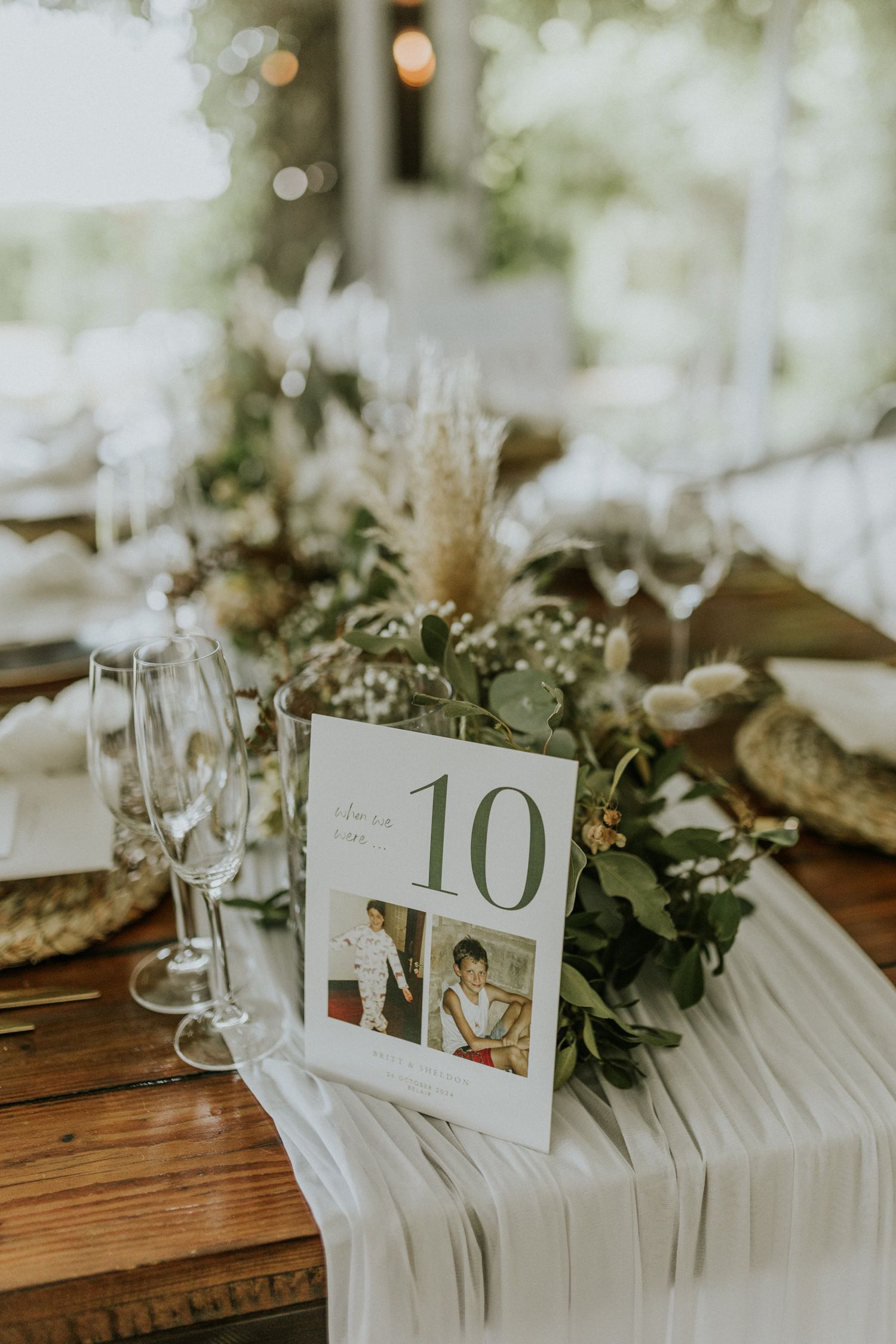Elegant wedding table number 10 with greenery garland and champagne flutes.