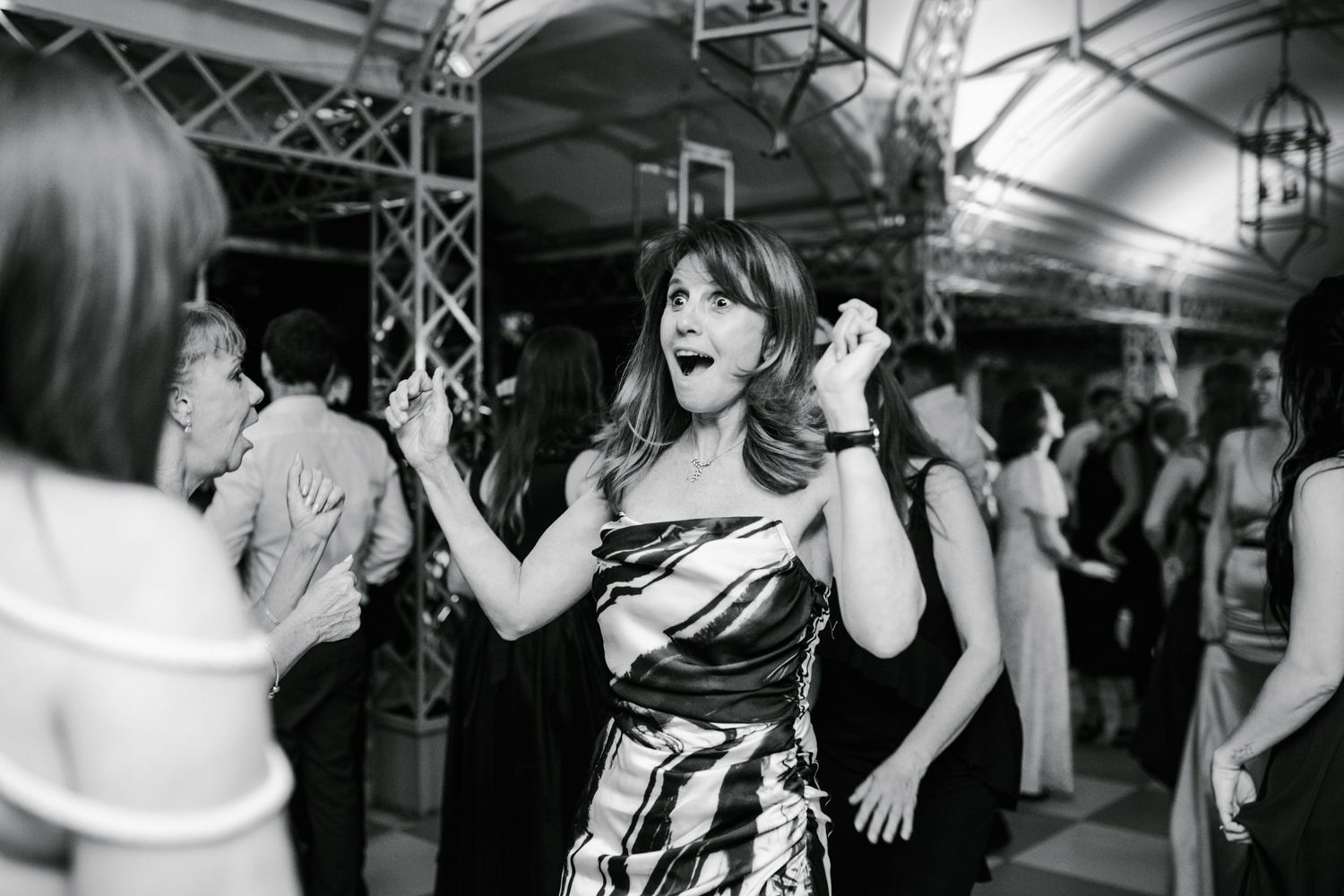 Excited woman in patterned dress dancing at elegant wedding reception celebration.