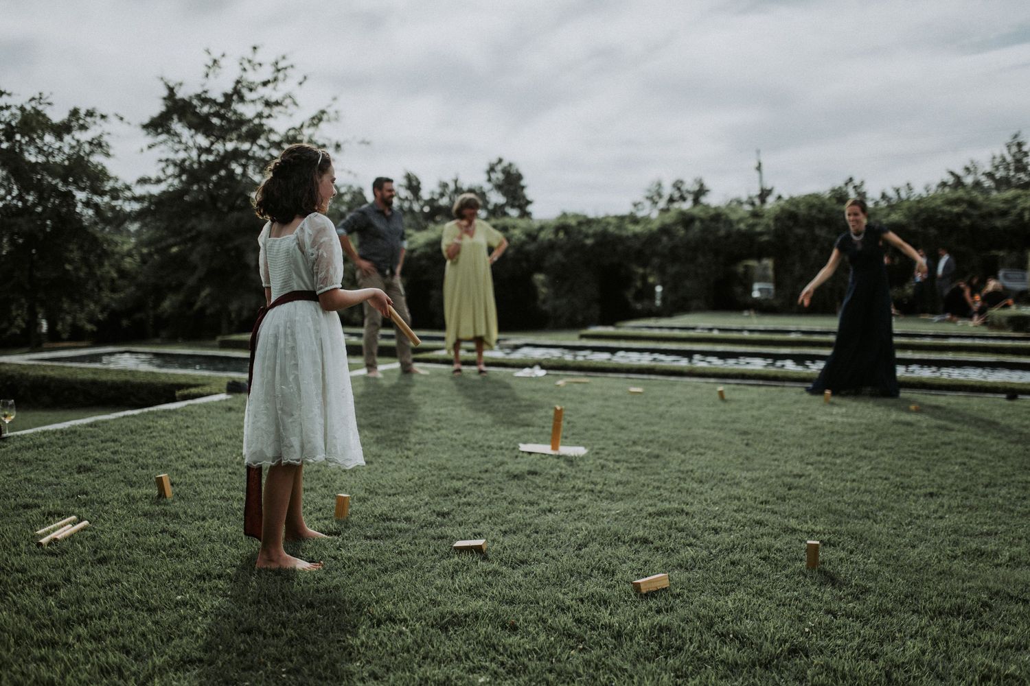 Children and guests playing lawn games on green grass at an outdoor wedding reception.