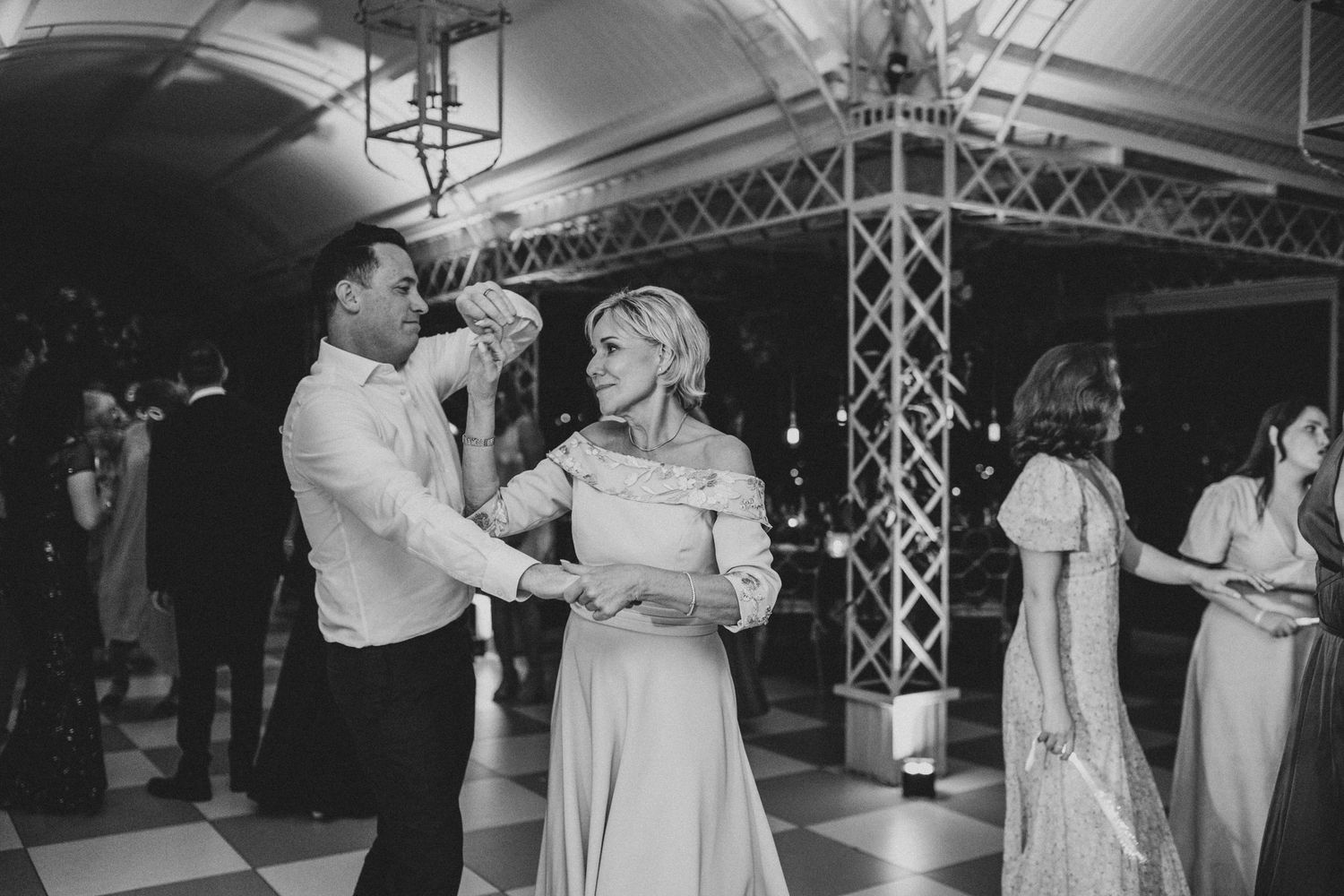 Couple sharing elegant slow dance together on checkered floor at sophisticated wedding reception venue.
