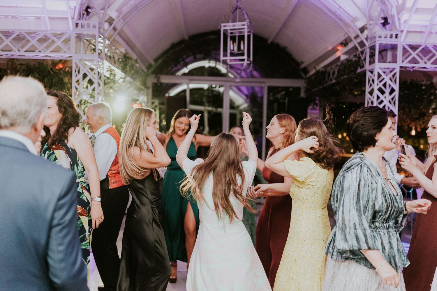 Energetic wedding guests dancing together under warm lights at festive reception.