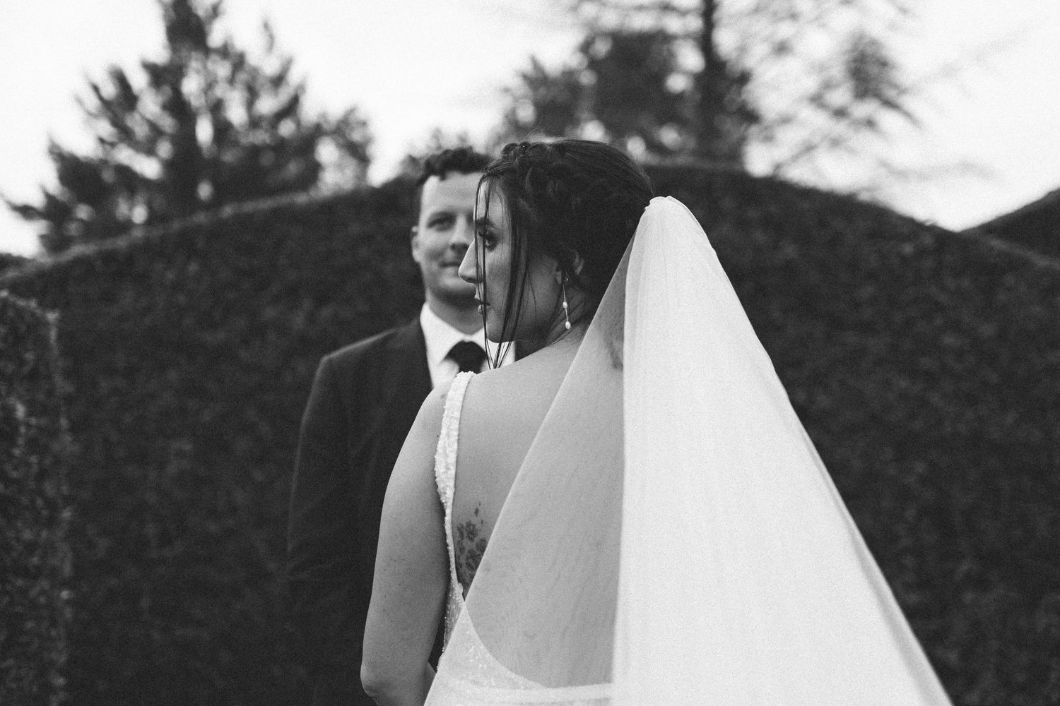 Romantic black and white portrait of bride and groom sharing an intimate moment beneath a flowing veil.