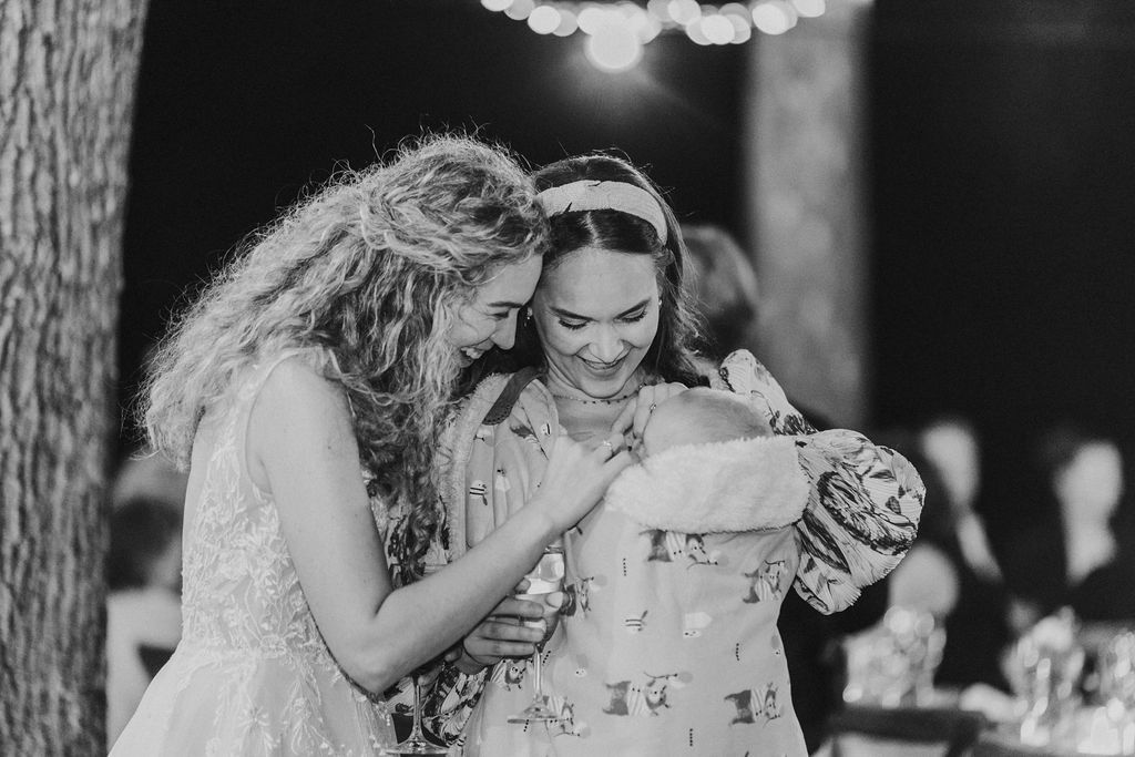 Black and white photo of bride sharing a joyful moment with a guest at wedding reception.