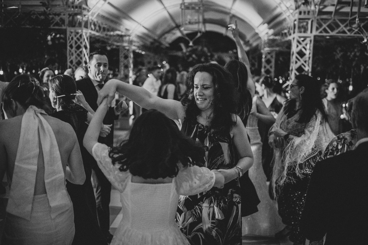 Wedding guests laughing and dancing together at lively indoor reception celebration.