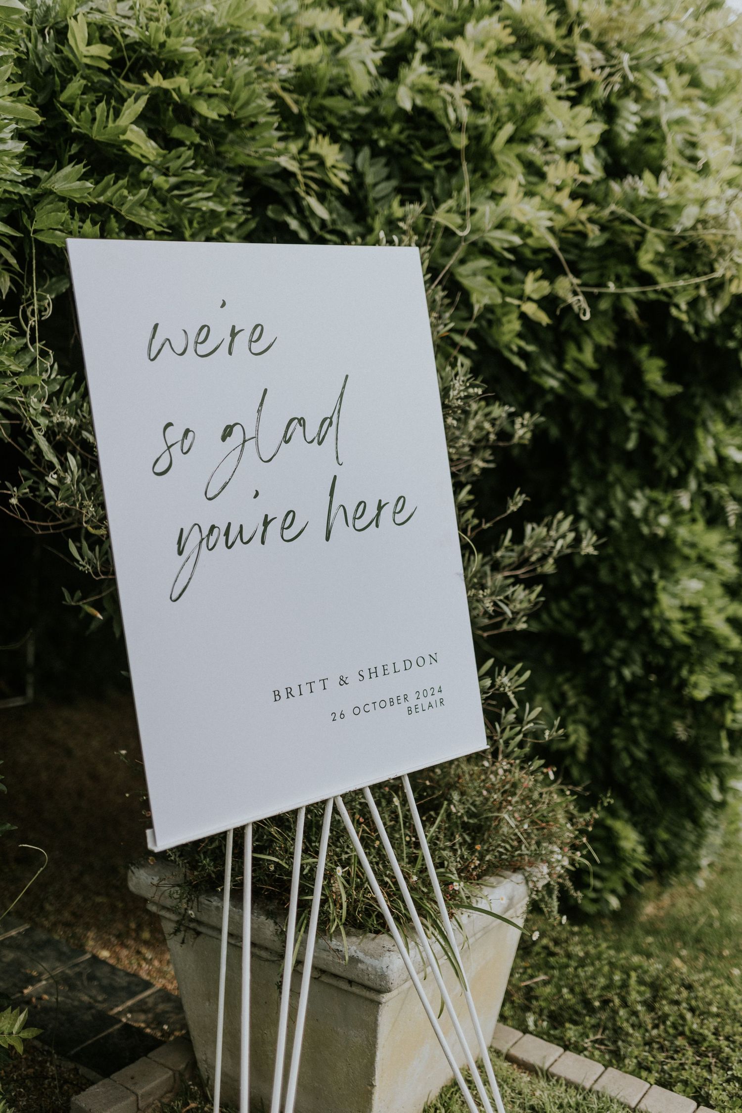 Elegant white wedding welcome sign reading we are so glad you are here for Britt and Sheldon October 2024.