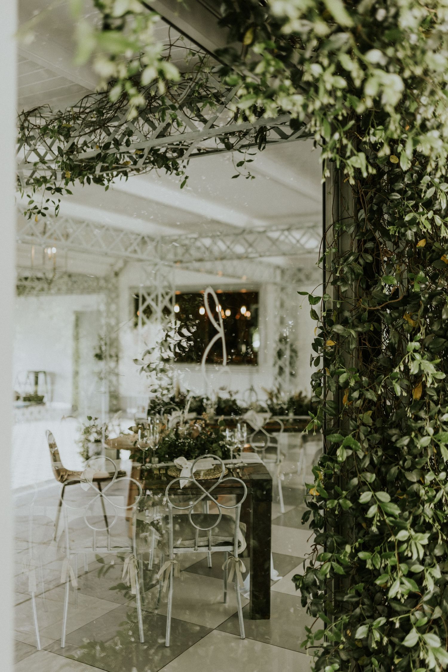Elegant wedding venue interior adorned with cascading green vines and white lattice decor.