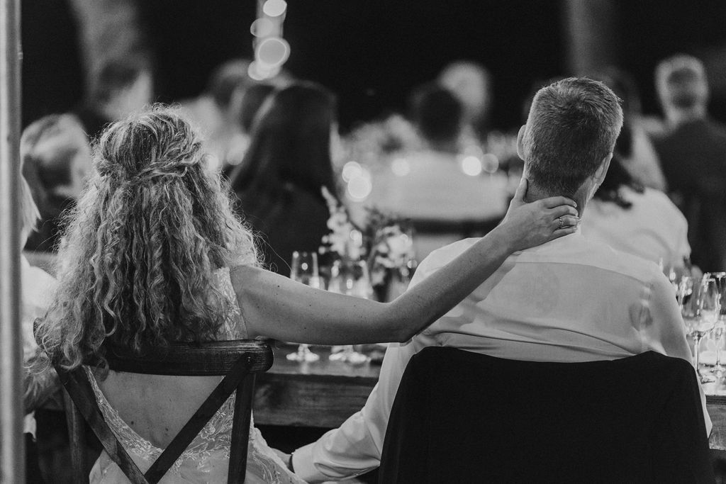 Bride with curly hair and groom viewed from behind at romantic outdoor wedding reception.