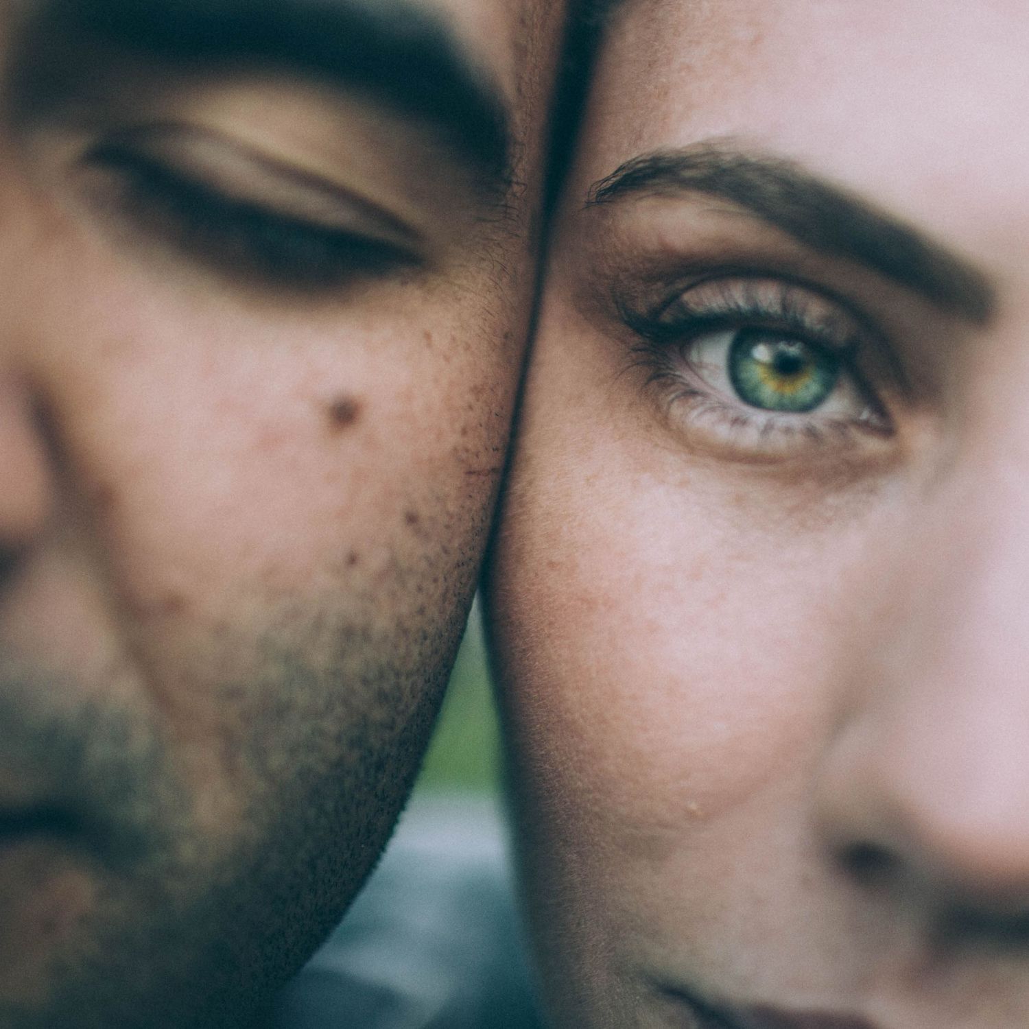 Intimate close-up portrait of a couple with foreheads touching, highlighting the womans striking green eyes.