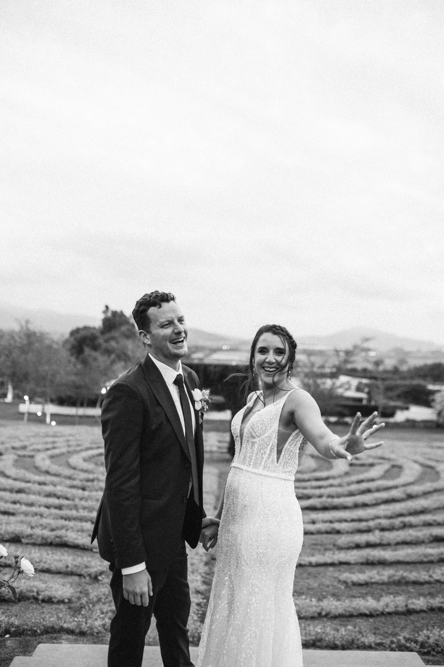 Joyful bride and groom posing in black and white photo with lavender field in background.
