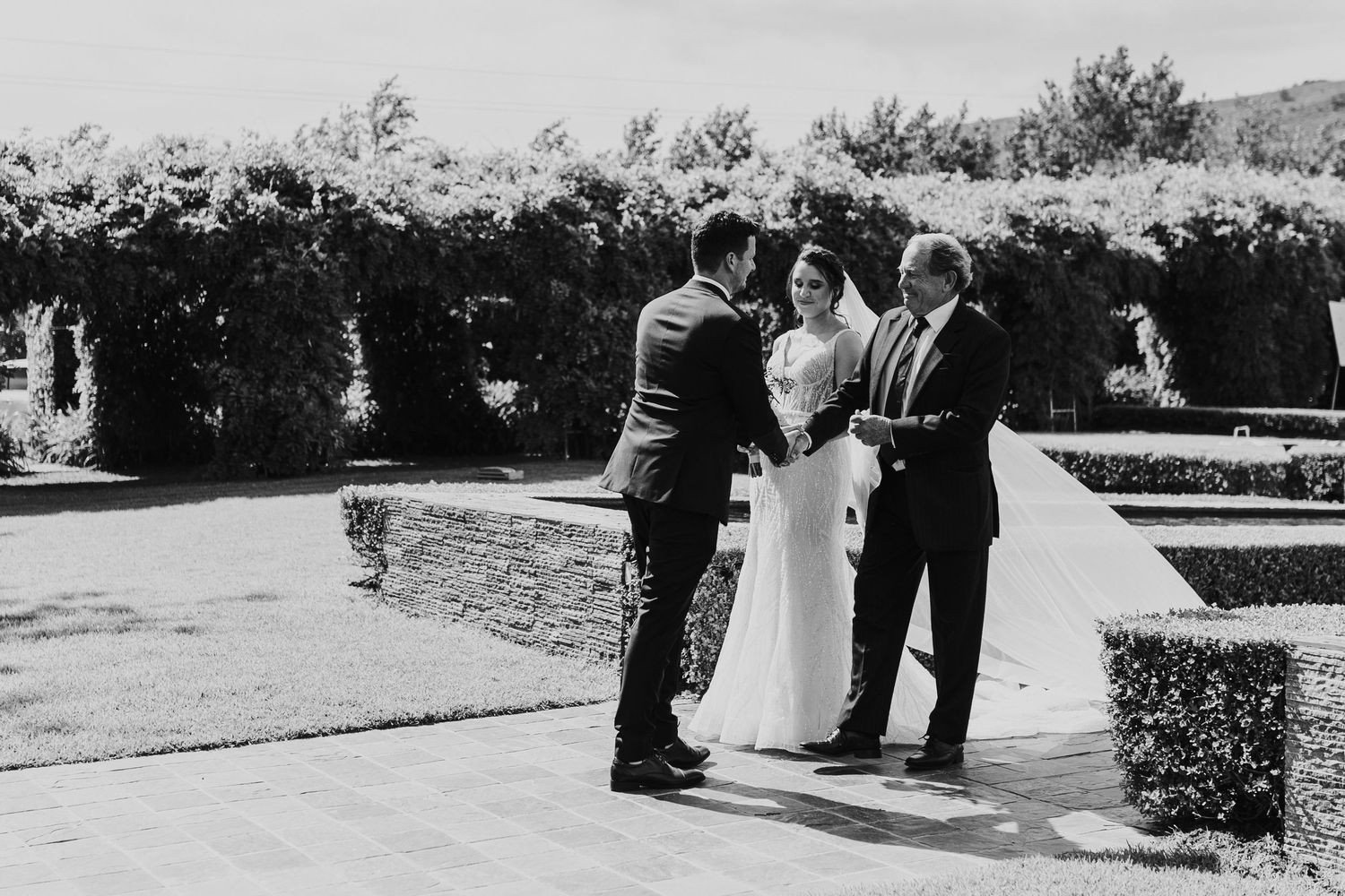 Black and white photo of wedding ceremony with couple exchanging vows outdoors.