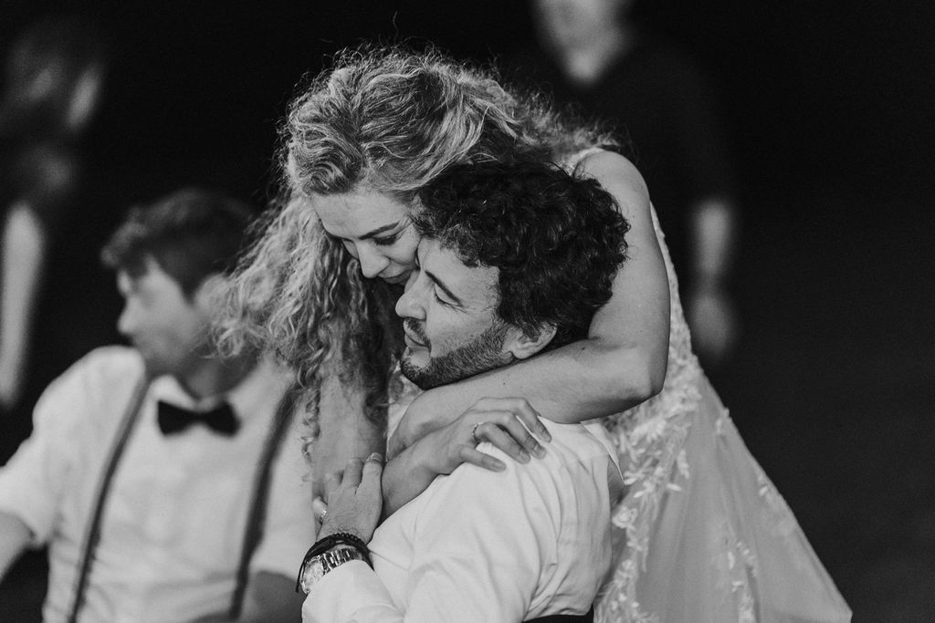 Emotional black and white wedding photo of bride embracing groom during their first dance celebration.