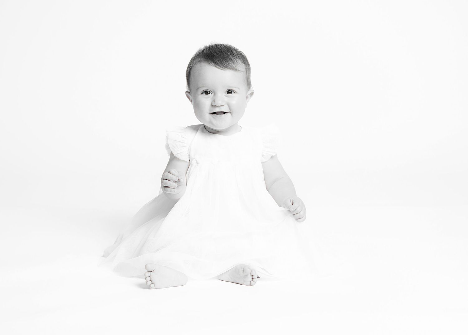 A black and white photo series showing a baby's developmental stages from lying down to sitting up.