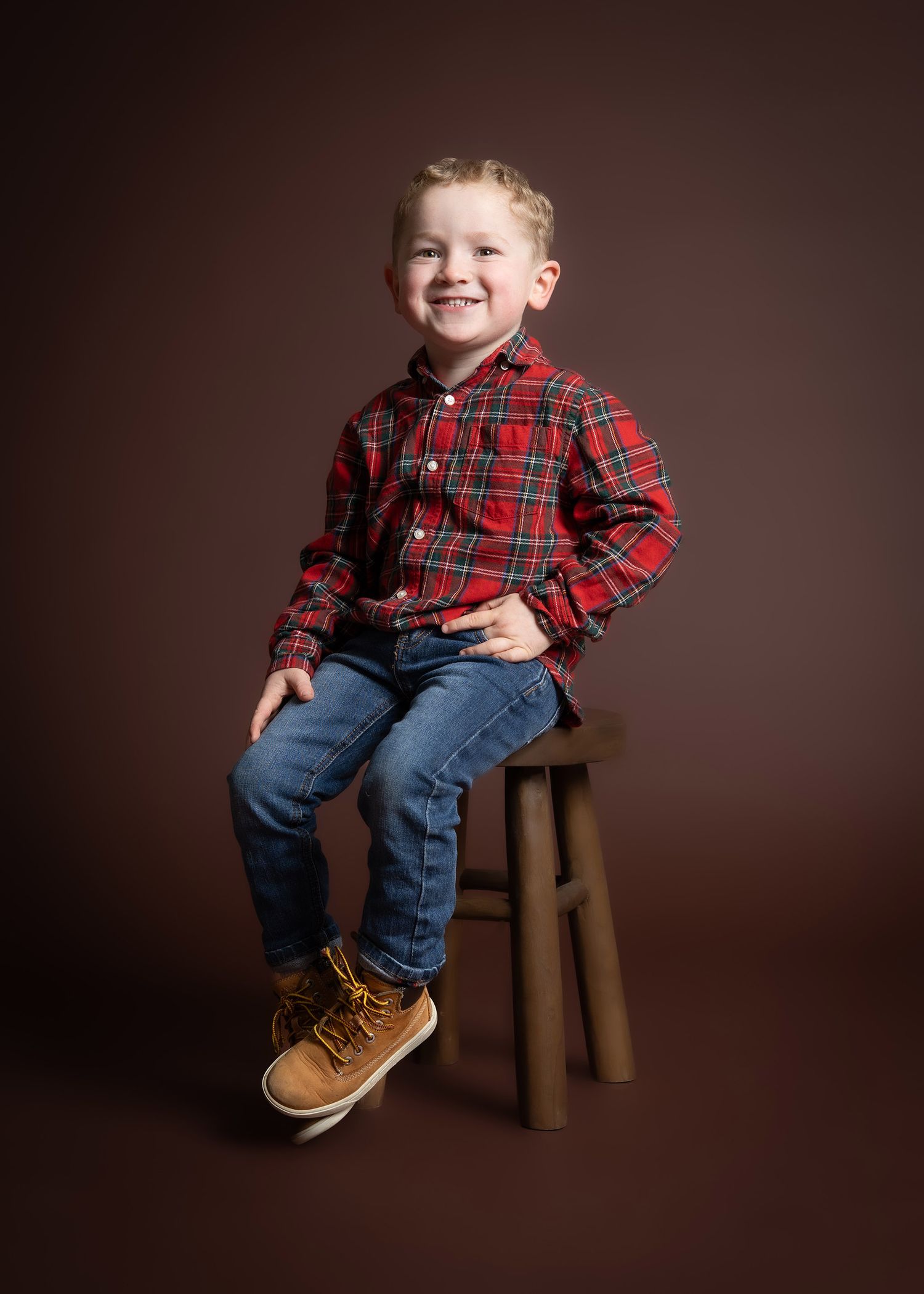 A series of portrait shots showing a young child in a red plaid shirt and jeans sitting and posing on a wooden stool in Telford