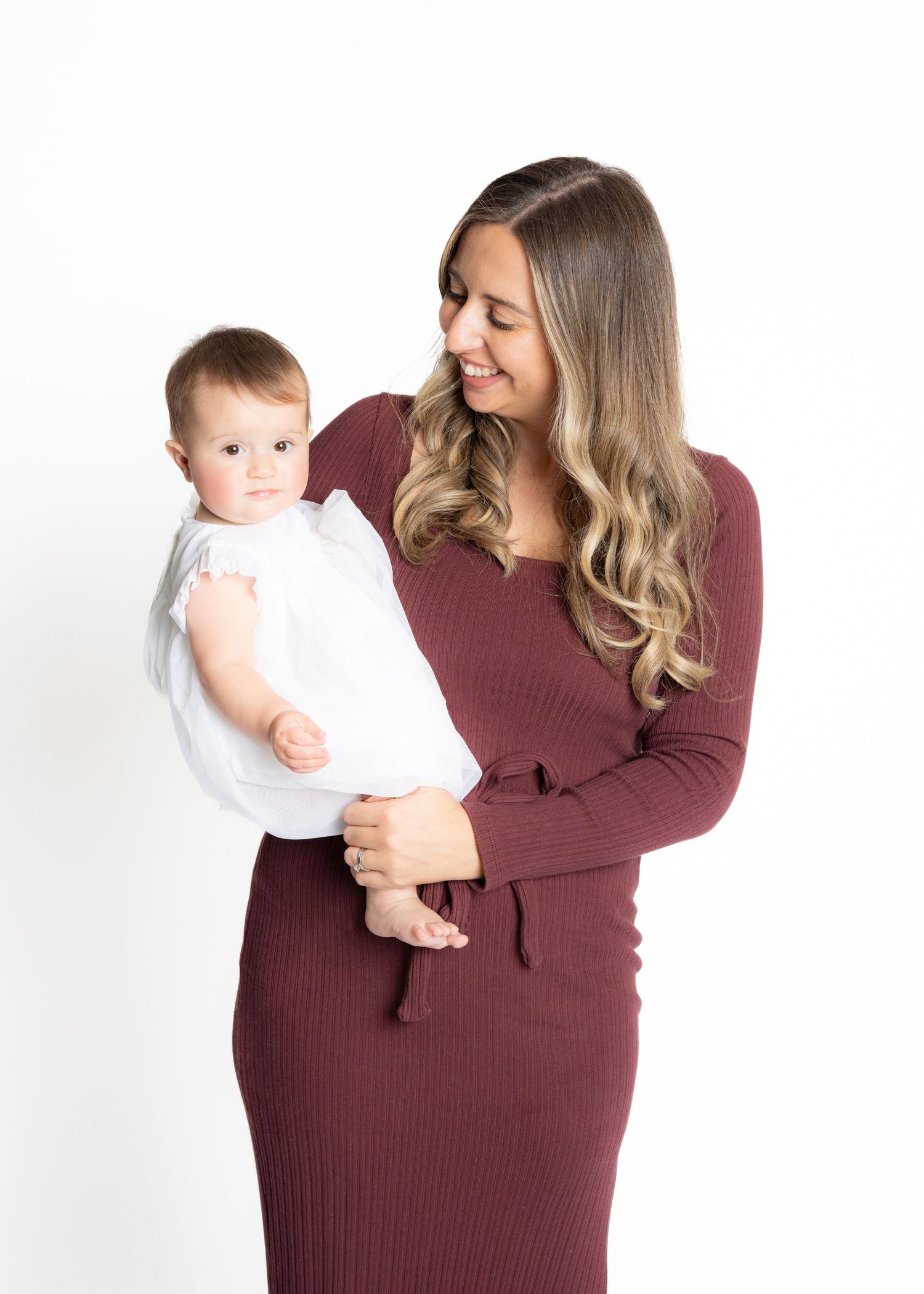 Woman in burgundy sweater holds and plays with baby in white onesie showing progression of loving interaction.