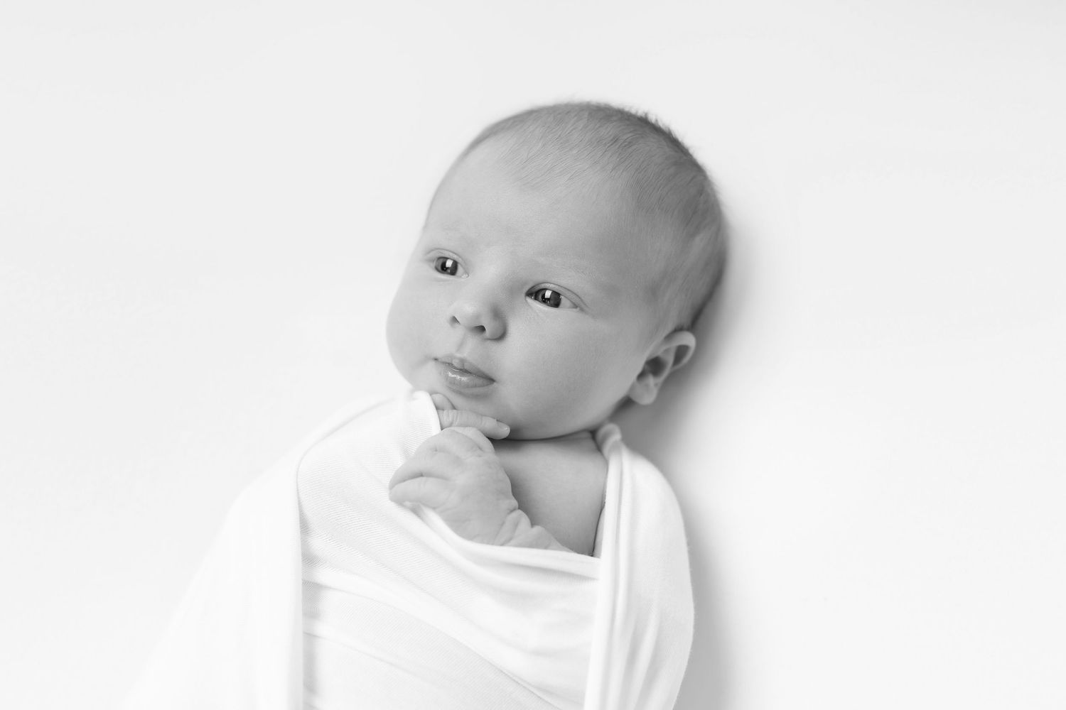 Four sequential black and white photos show a baby resting its head on white fabric from different angles.